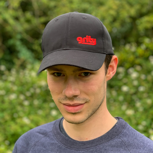 Man in the country wearing a black cap with a red grity logo